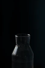 Close-up of a dark glass coffee bottle with subtle gold accents on a black background.