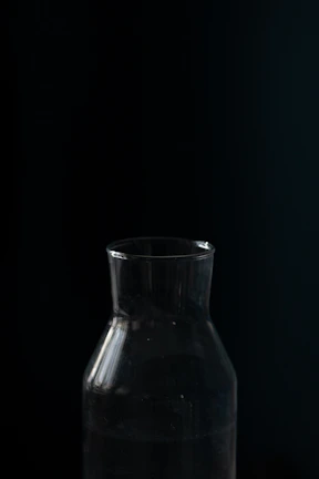 Close-up of the heavy glass bottle catching light against a matte black background.