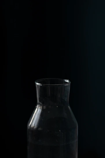 A minimalist, slightly eerie bottle of Kinzer apple iced tea glowing softly against a dark, empty background.