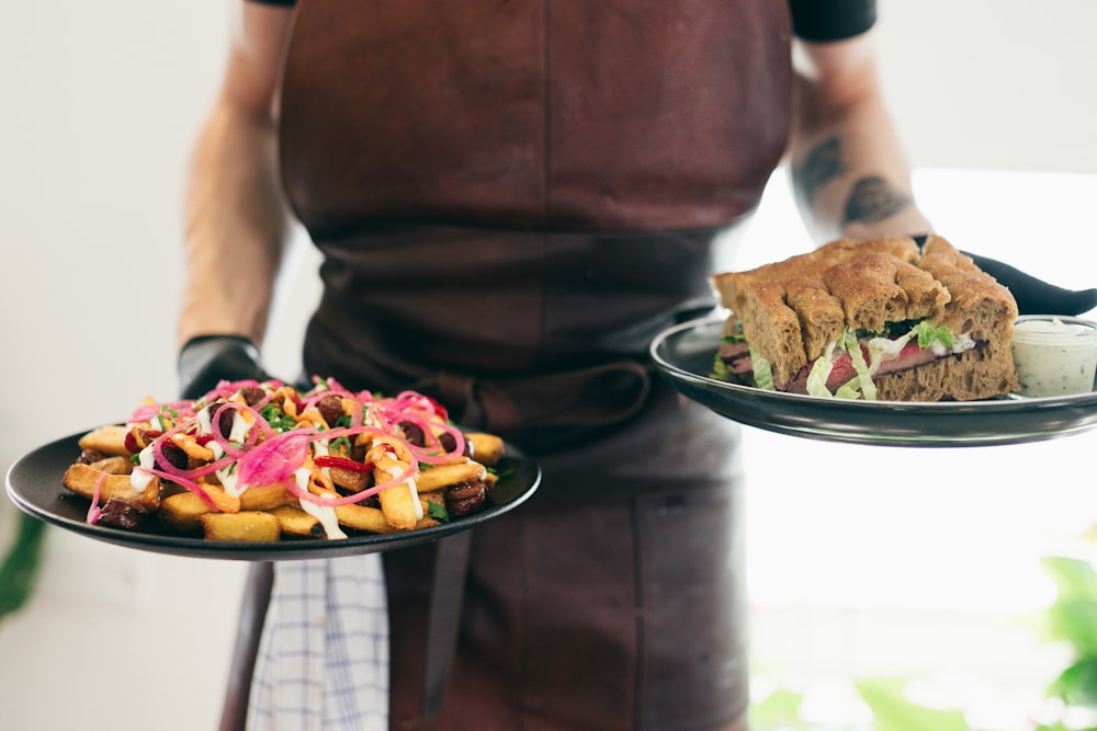 a man in an apron holding two plates of food