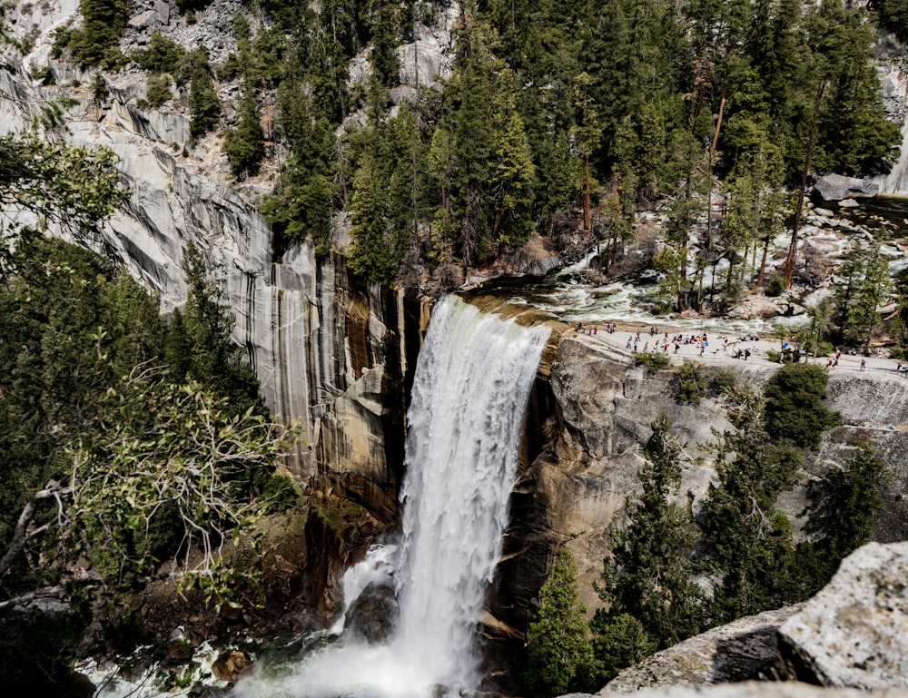 a waterfall with people standing at the top of it