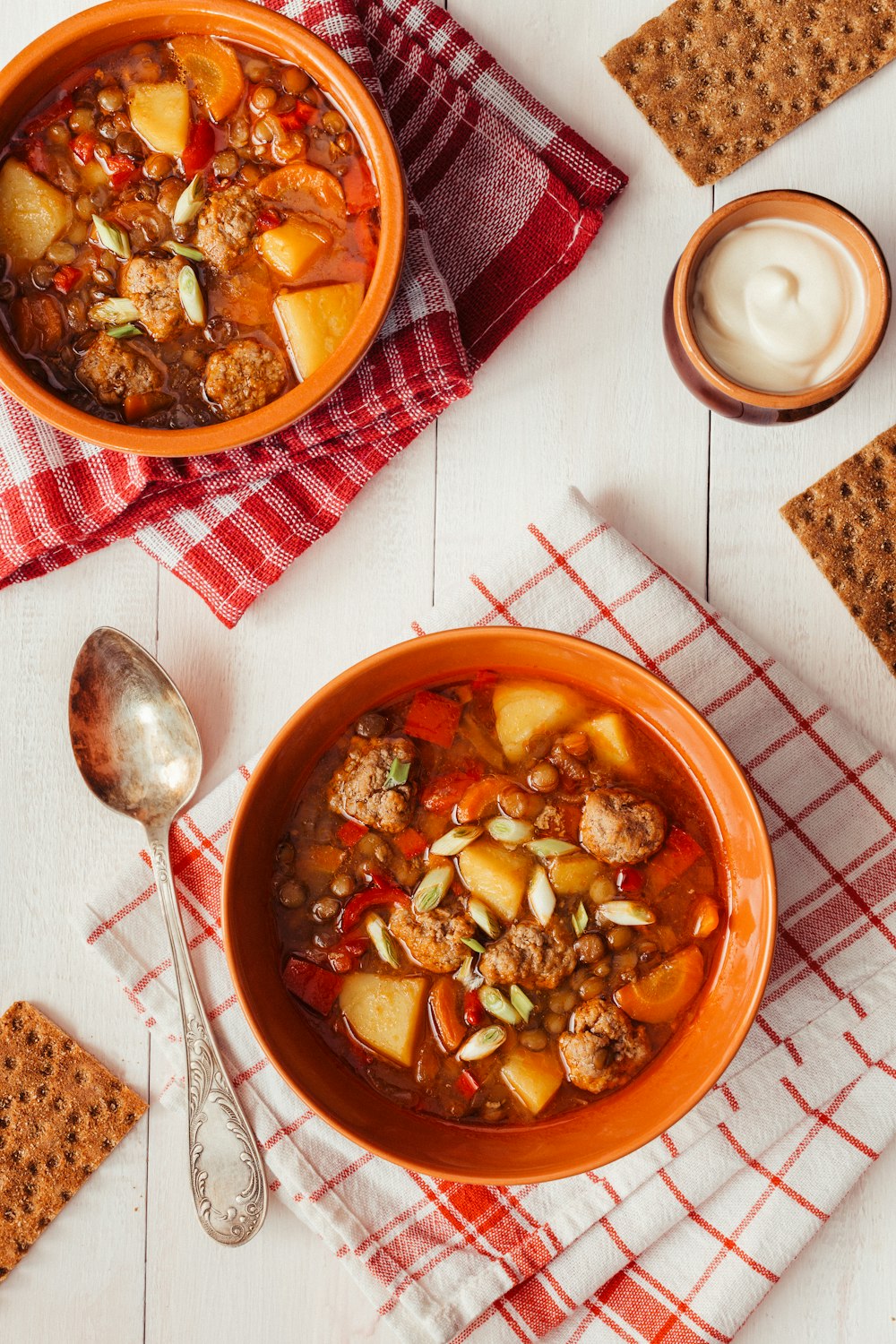 two bowls of soup on a table with crackers