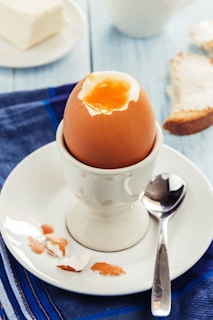 a cracked egg in a white bowl on a white plate