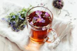 a glass mug filled with tea next to a bunch of flowers