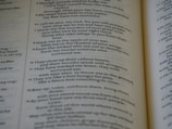 A close-up view of an open book displaying text arranged in verses. The page features a passage with numbered lines and is printed in a serif font. The focus is on a section discussing themes of protection and refuge.