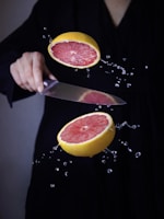 a person cutting a grapefruit with a knife