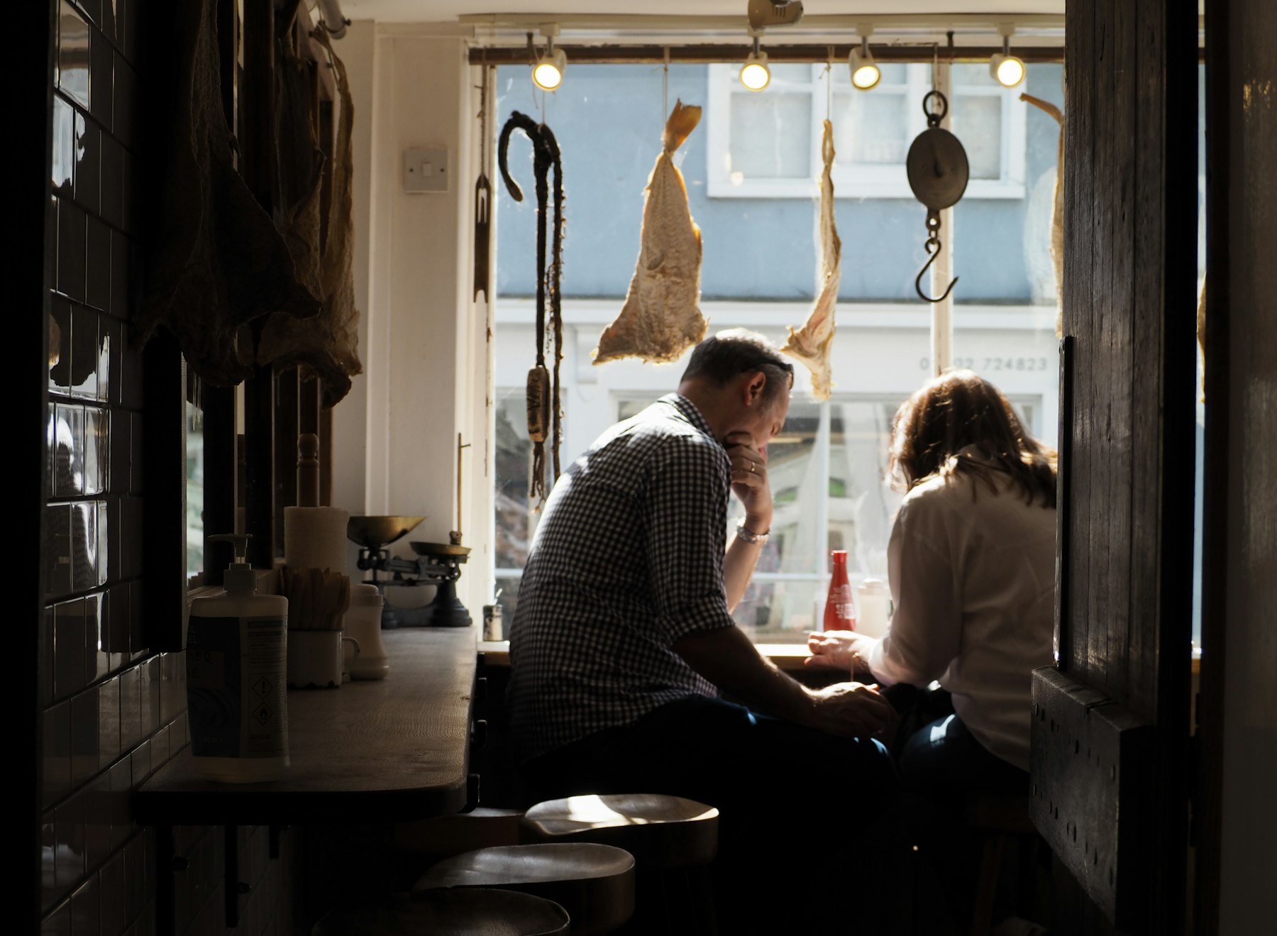 A couple sitting together at a window, having a quiet conversation