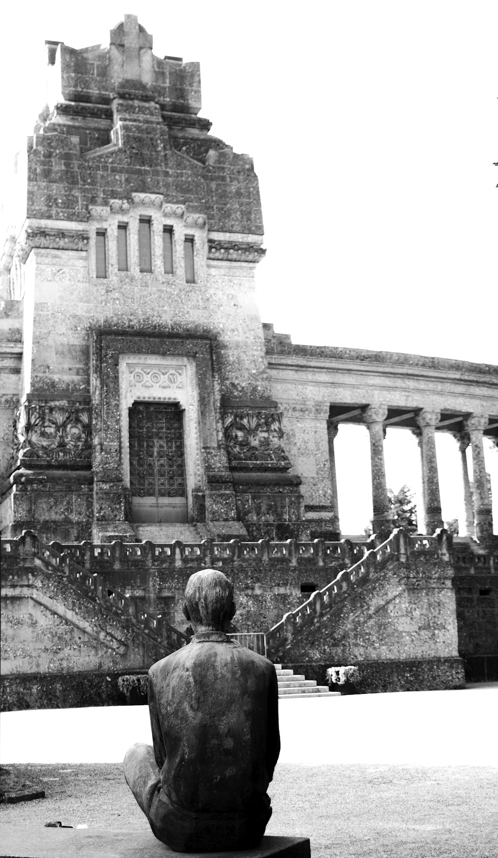 a statue of a man sitting in front of a building