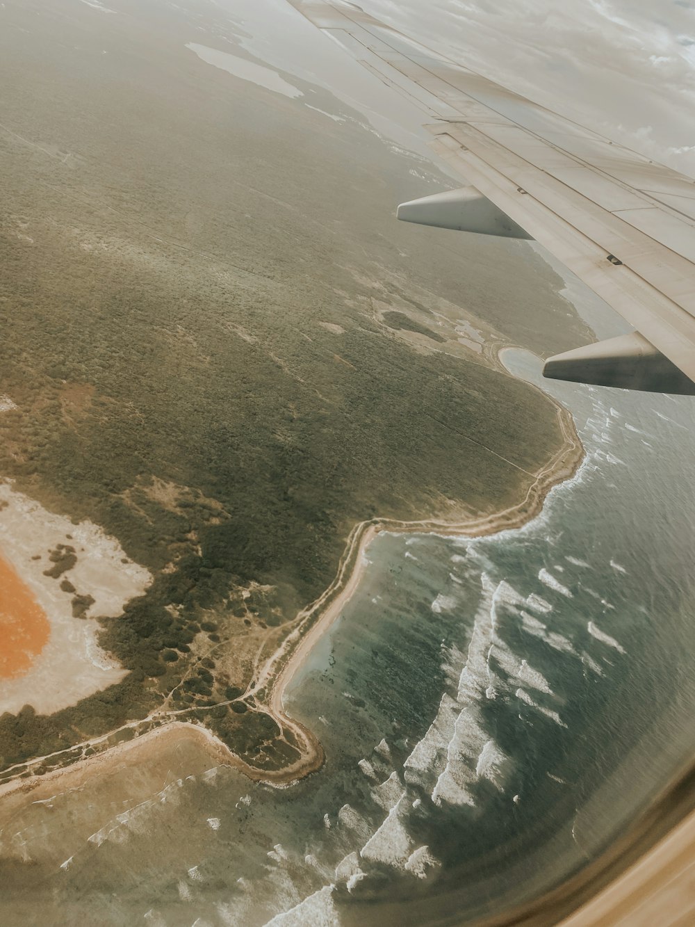 an airplane wing flying over a body of water