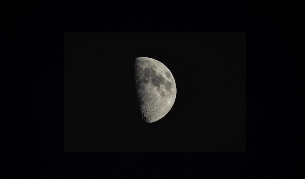 a half moon is seen in the dark sky