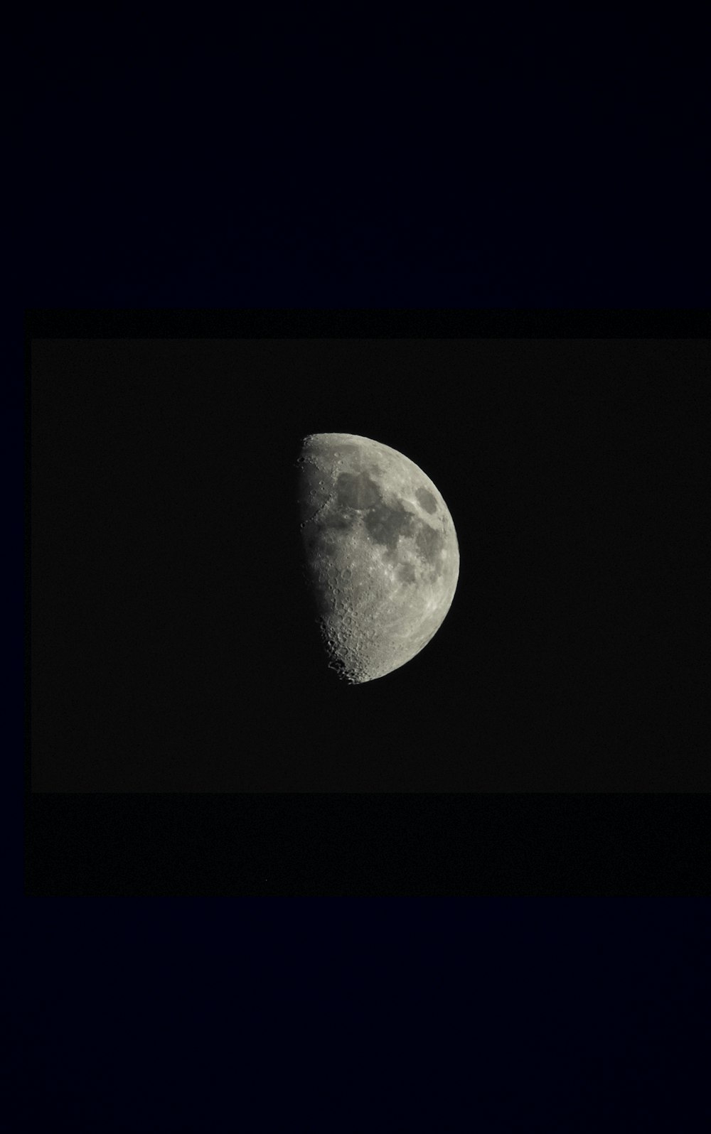 a half moon is seen in the dark sky