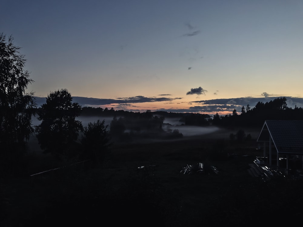 the sun is setting over a foggy field