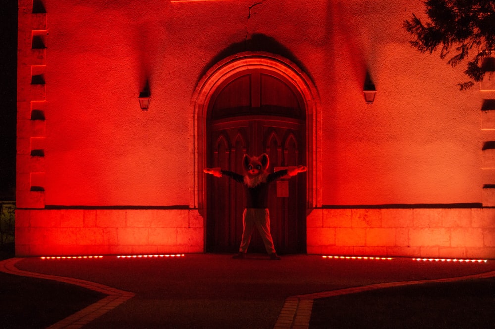 a man standing in front of a red lit building