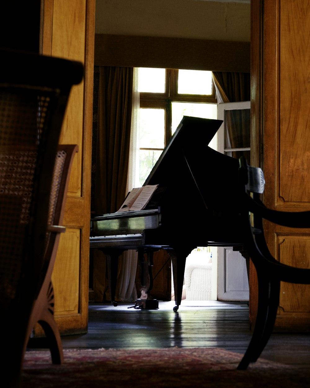 a grand piano sitting in a living room next to a chair