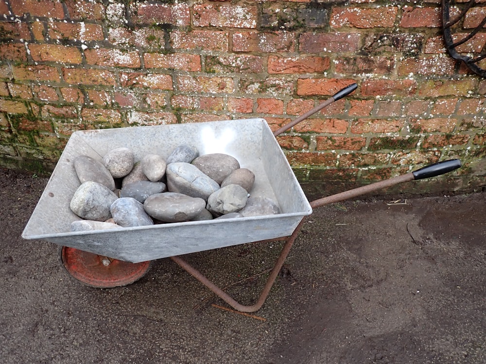 a wheelbarrow filled with rocks sitting next to a brick wall