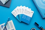 A series of cards labeled 'Brand Positioning' are displayed on a blue surface. The cards have blue and white sections, featuring text about strategic brand concepts. Nearby are a blue pen, a color swatch card, a book with circular patterns on the cover, and a black and blue marker. The arrangement is neat and organized, suggesting a theme of branding and design.