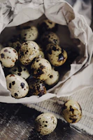 Fresh quail eggs in a natural straw basket with soft sunlight.