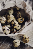 A basket filled with freshly collected quail eggs, resting on a wooden table.