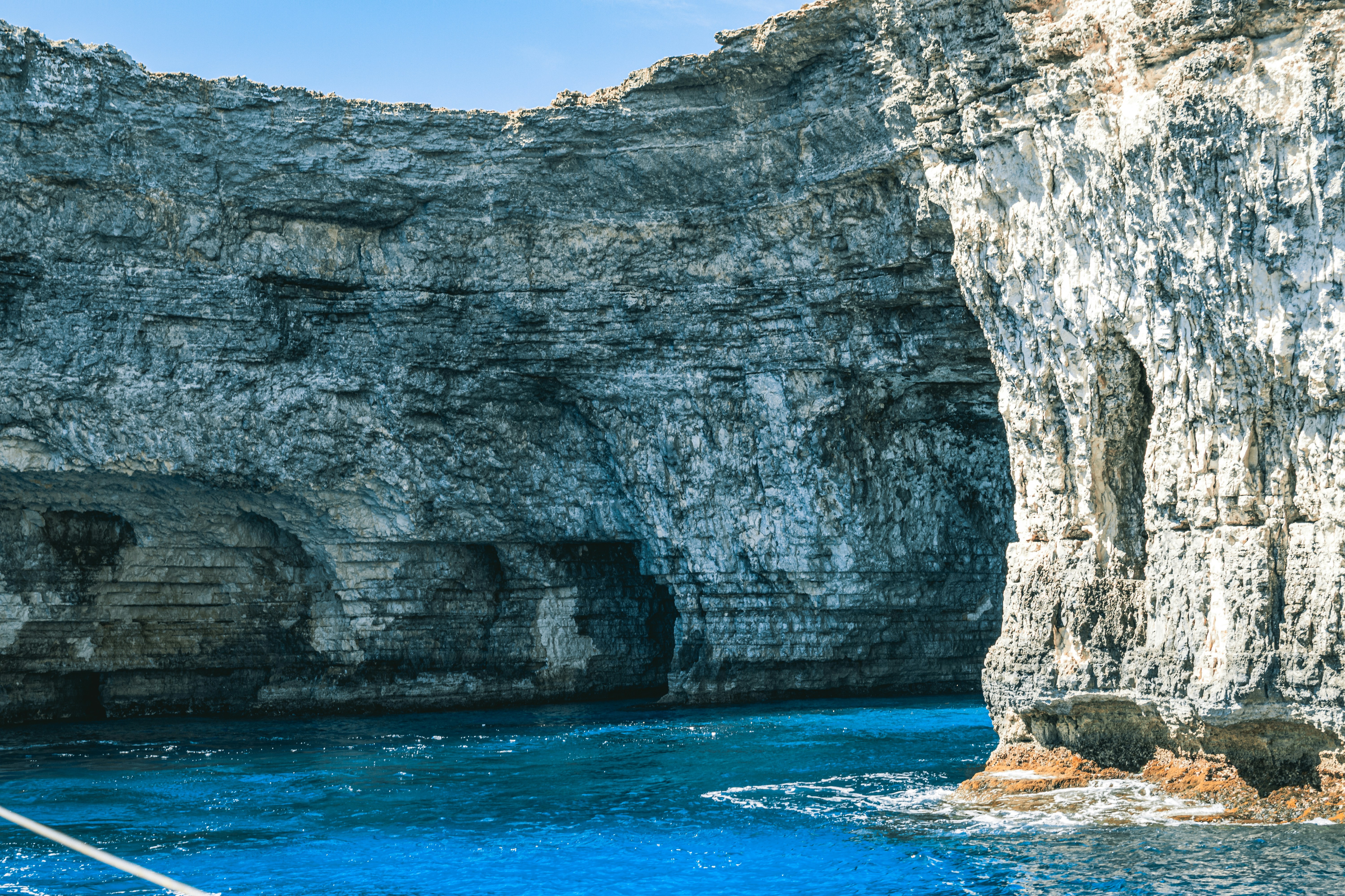 a boat in a body of water near a rocky cliff