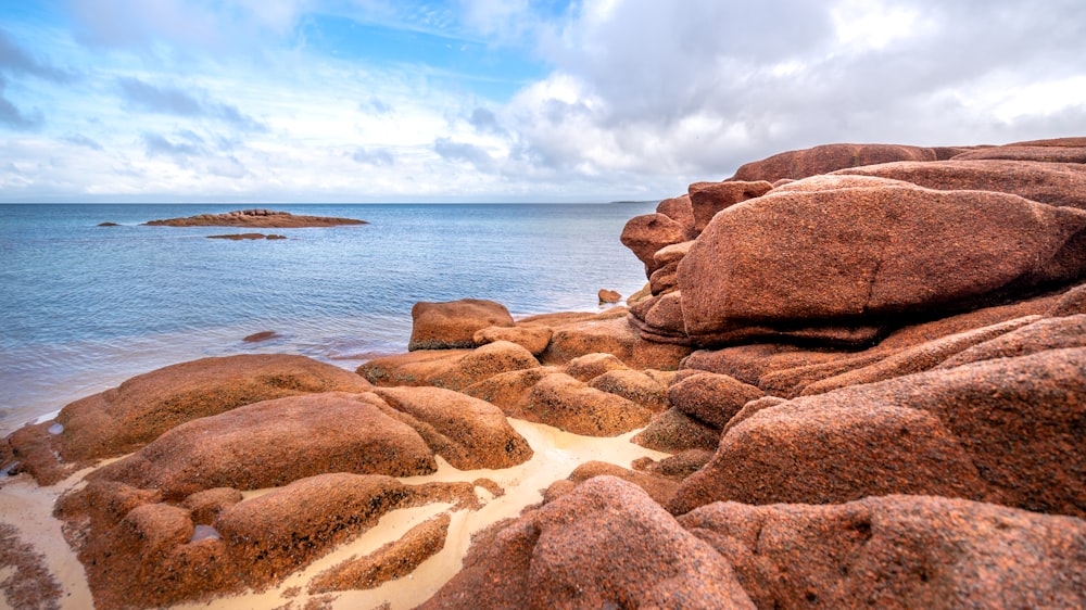 a rocky beach with a body of water in the background