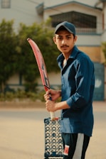 A young cricketer proudly holding a bat on a sunny cricket field.