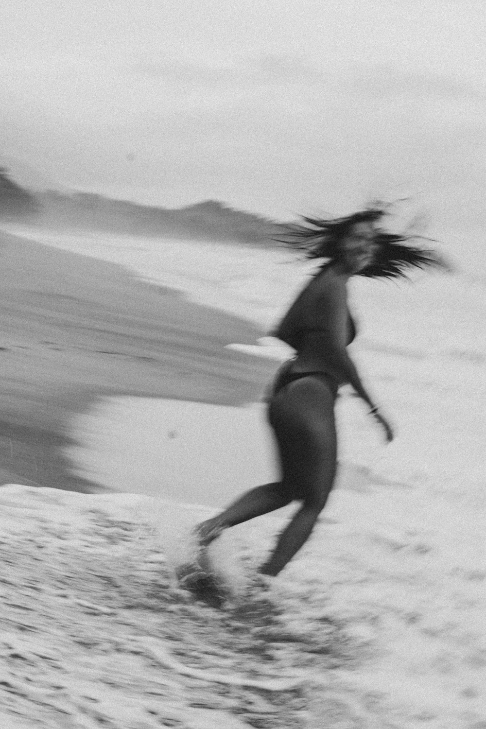 a woman in a wet suit running on the beach