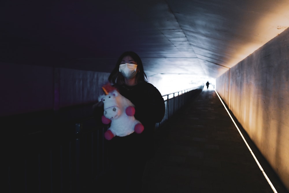 a woman wearing a face mask holding a stuffed animal