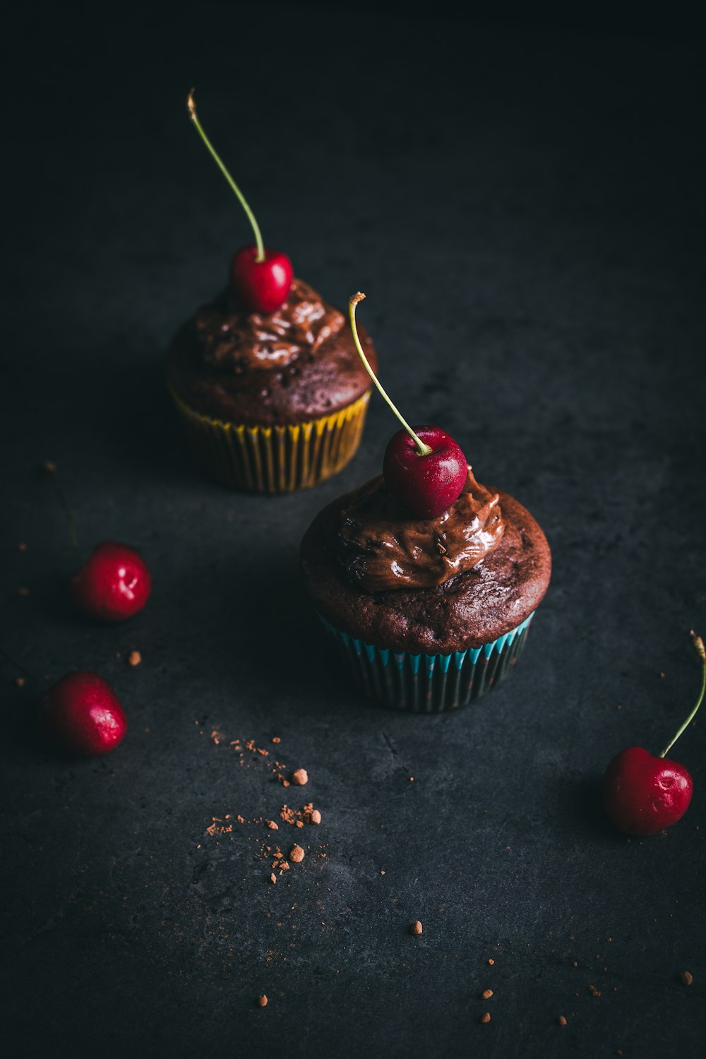 Dos cupcakes con glaseado de chocolate y cerezas