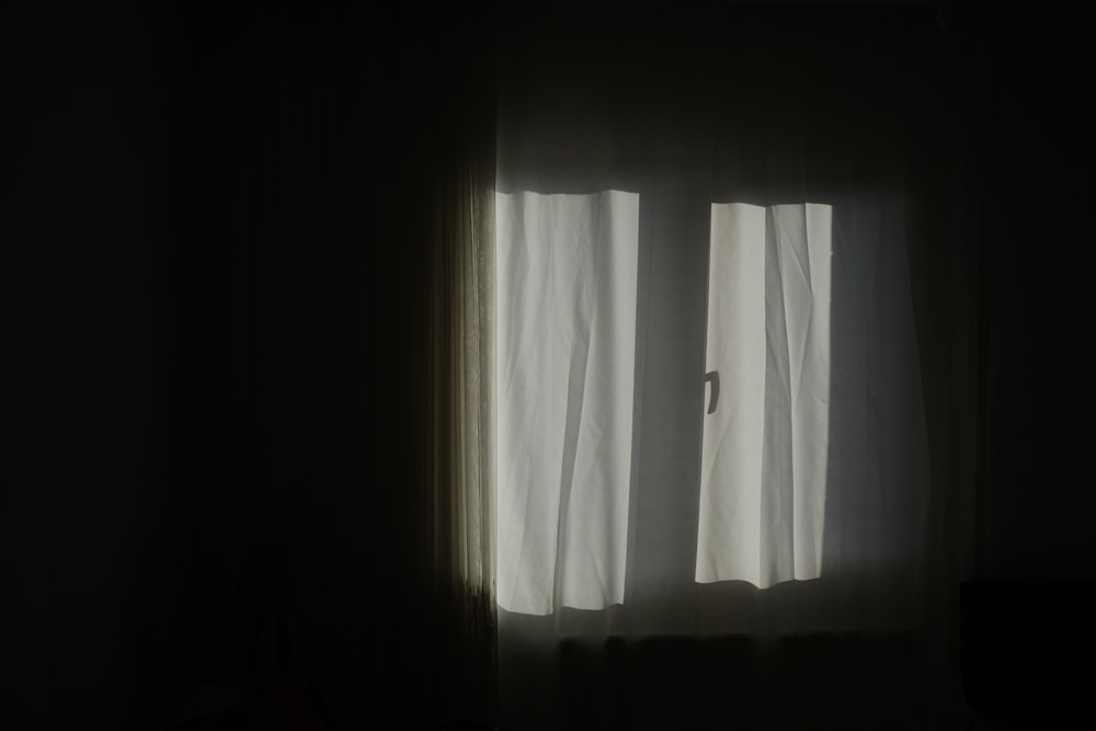 a dark room with a window and a curtain
