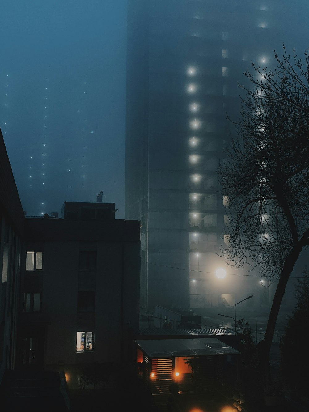 a foggy night in a city with buildings and street lights