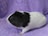 A guinea pig with black and white fur is sitting on a textured purple towel. The guinea pig is facing left, with its black fur covering the head and back, while the rest of the body is white.