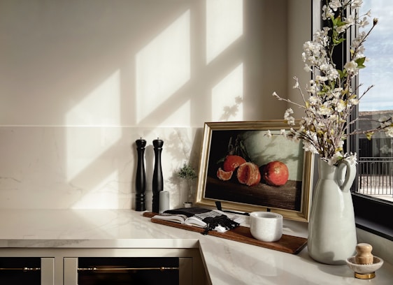 A serene kitchen countertop featuring neatly arranged minimalist everyday essentials bathed in natural light.