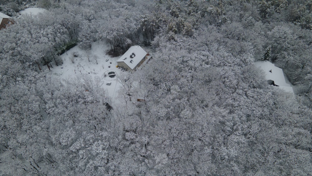 an aerial view of a house surrounded by trees covered in snow