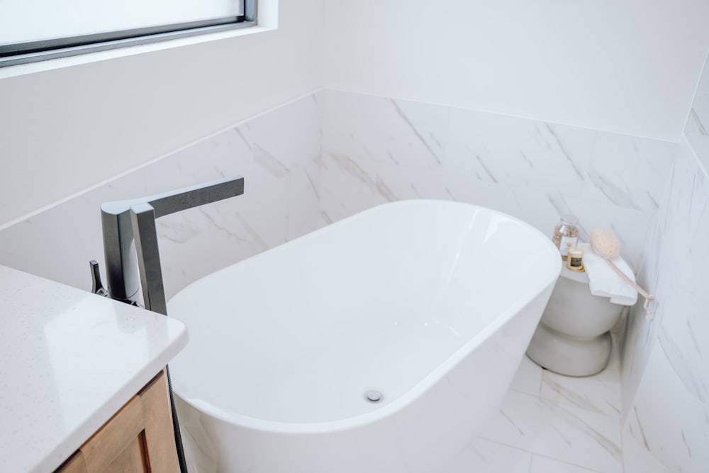 una bañera blanca sentada en un baño al lado de un inodoro