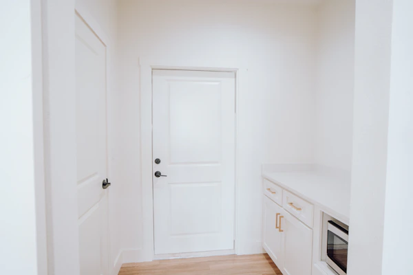 a kitchen with a white door and white cabinets
