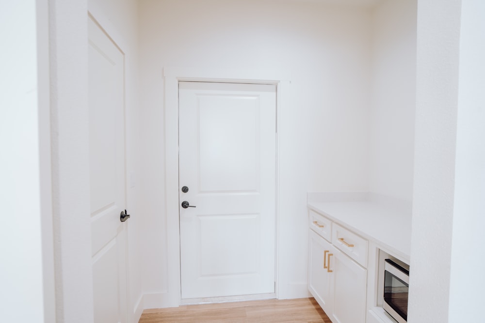 una cocina con una puerta blanca y armarios blancos