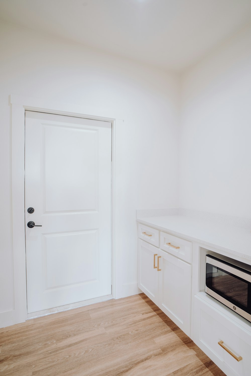 a white kitchen with a white door and white cabinets