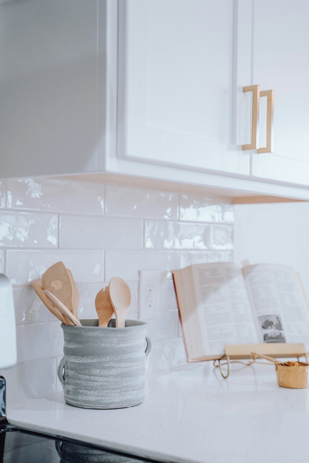 a kitchen counter with a book and wooden utensils