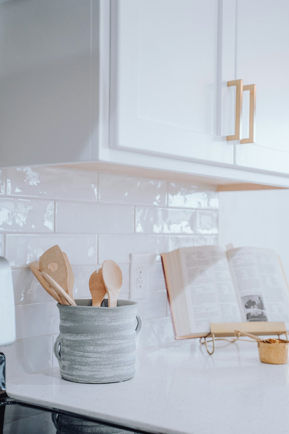 um balcão de cozinha com um livro e utensílios de madeira