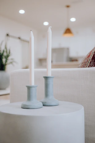 An arrangement of nude and white candles with subtle shadows, styled with minimalist decor in a cozy room.