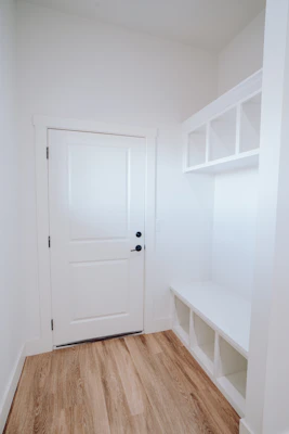 A distressed wood compact entry bench with a rustic finish, placed by a bright front door.