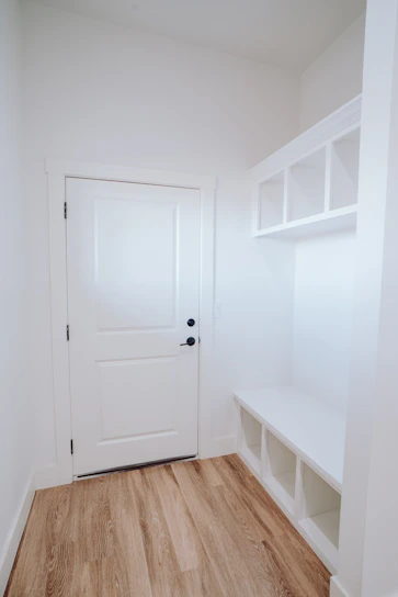 A narrow hall cubby shoe bench unit made of warm distressed wood, placed in a cozy entryway with sunlight streaming in.