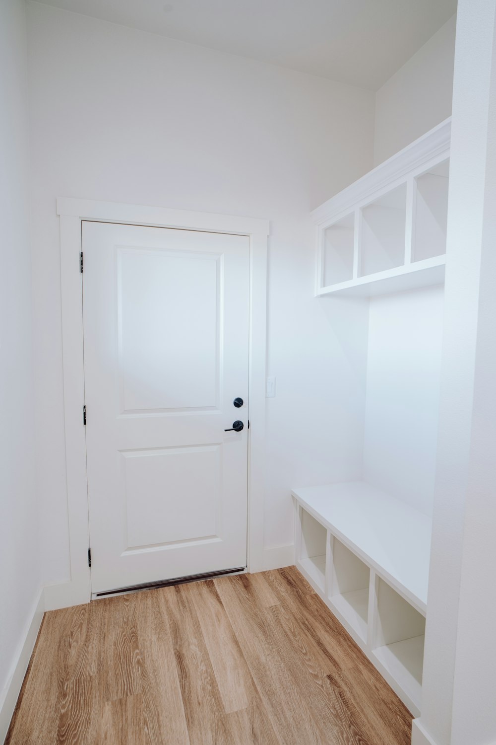 a white room with a wooden floor and a white door