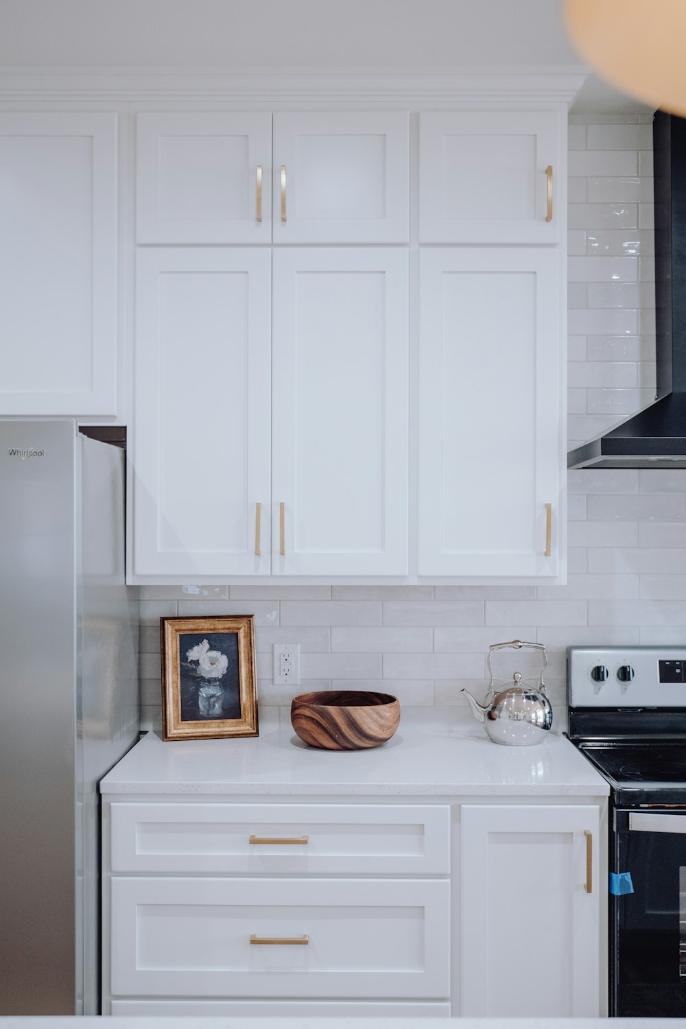 eine Küche mit weißen Schränken und einem silbernen Kühlschrank