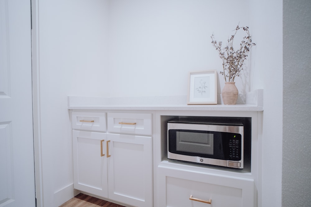 una cocina con armarios blancos y microondas