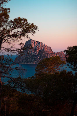 Sunset over the Las Rocas island, highlighting the terrain and mountain backdrop.
