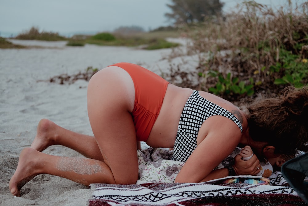 a woman in a bikini laying on a towel on the beach