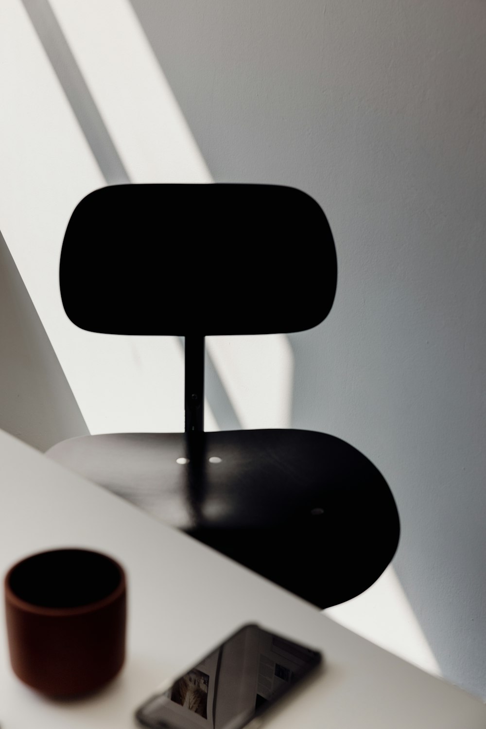 a white desk with a black chair and a cell phone