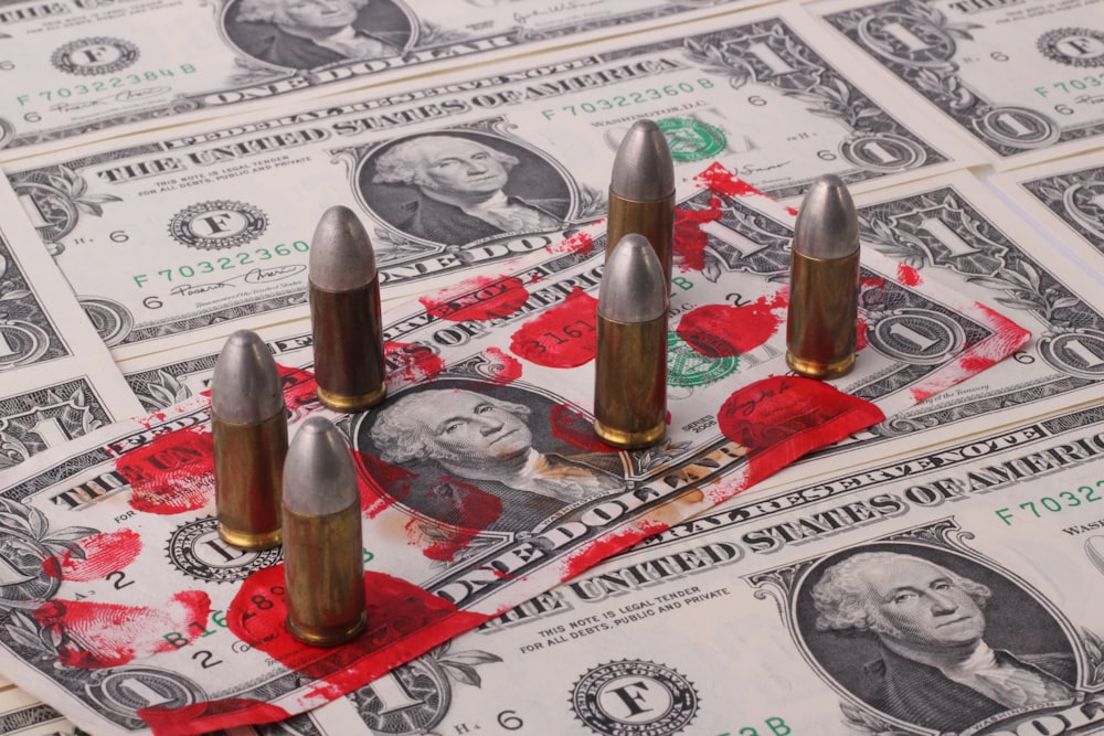 a pile of money with bullet shells on top of it