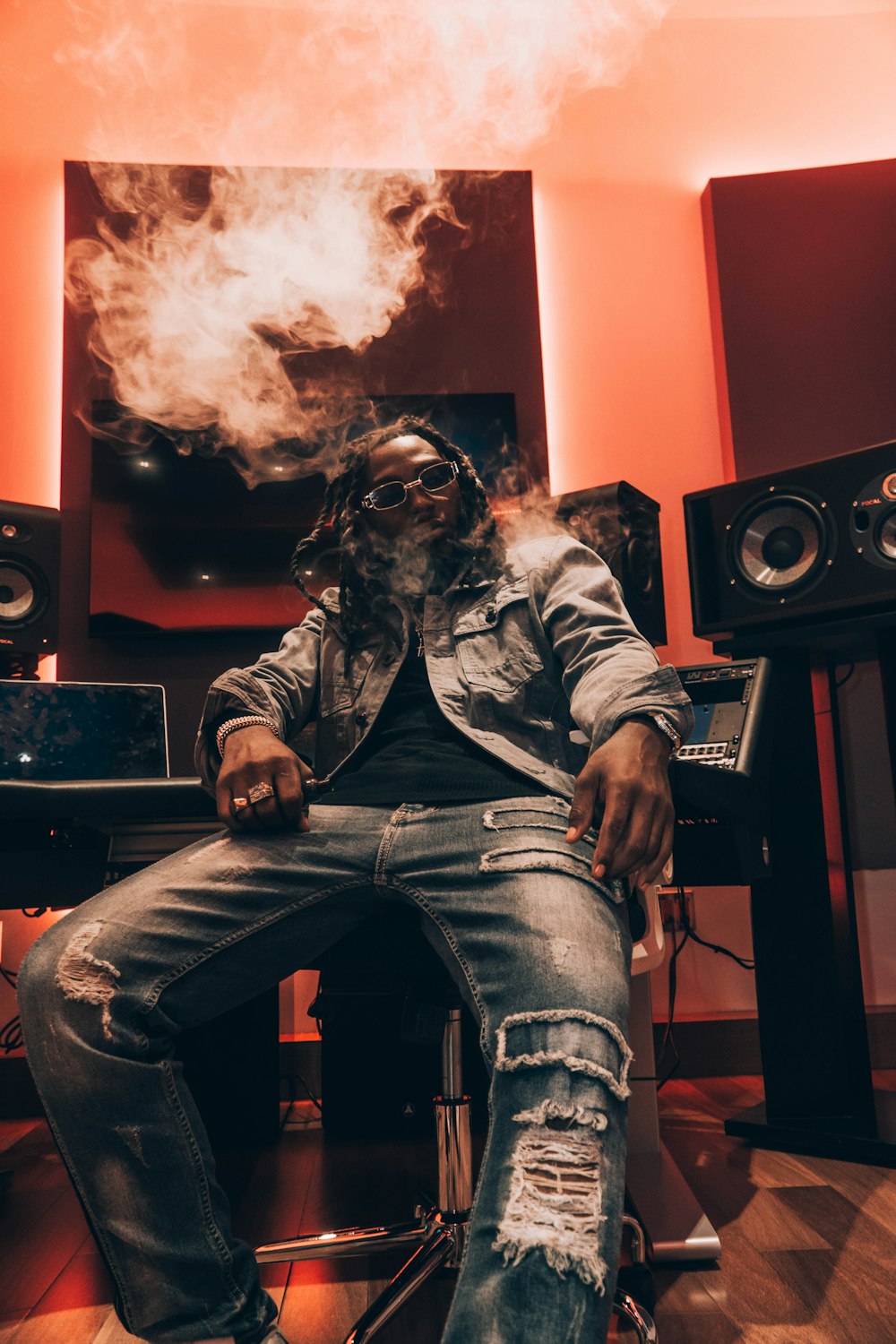 a man sitting on a stool in front of a set of speakers